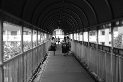 Rear view of people walking on bridge in city