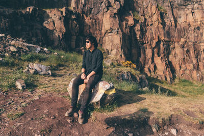 Man sitting on rock against mountain