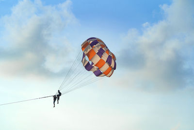 Low angle view of person paragliding against sky