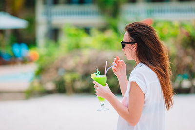 Midsection of woman holding ice cream standing outdoors