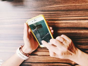 Midsection of person holding mobile phone on table
