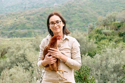 Woman holding brown hen in her hands in the farm. free-grazing domestic hen on organic farm.
