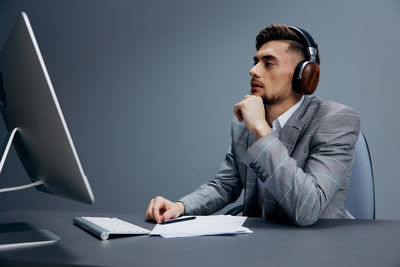 Young businessman wearing headphones looking at computer