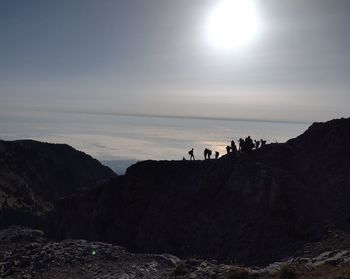 Scenic view of sea by silhouette mountain against sky