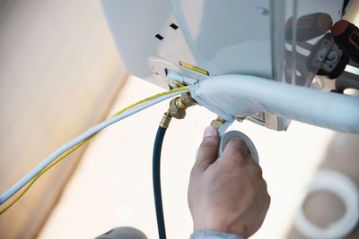 Man is installing wall compressor of air conditioner during hot season