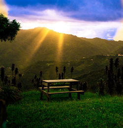 View of bench on landscape against sky during sunset