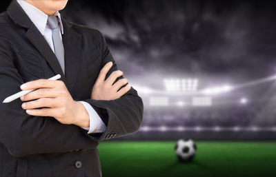 Midsection of businessman standing on soccer field