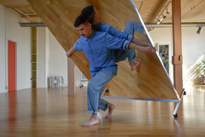 Side view of young man standing on hardwood floor at home