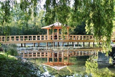 A wooden bridge and a gazebo across the river in a picturesque garden