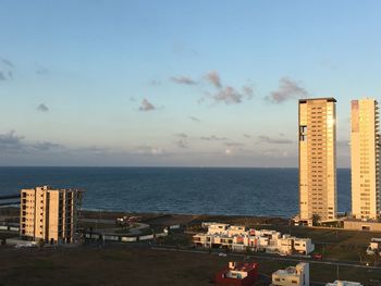 Modern buildings by sea against sky in city