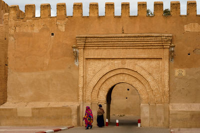 Rear view of people walking in tunnel