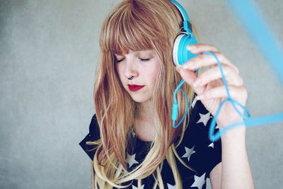 Young woman listening to music against gray background
