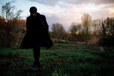 Rear view of man standing on field against sky