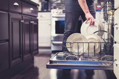 Midsection of man holding glass while standing in kitchen