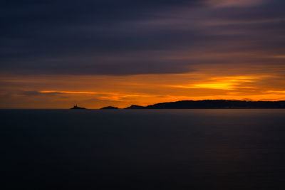 Scenic view of sea against cloudy sky during sunset