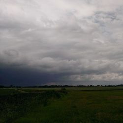 Scenic view of grassy field against cloudy sky