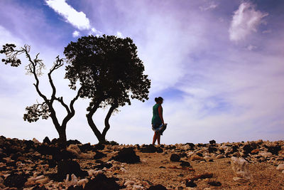 Man standing on rock against sky