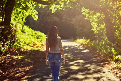 Rear view of woman walking along plants