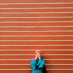 Woman covering face against wall