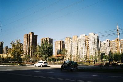 Cars on street by buildings against clear sky