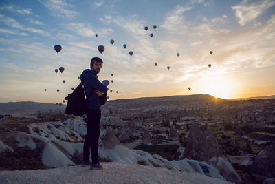 Man with backpack tourist standing on a rock at dawn with balloons cappadocia