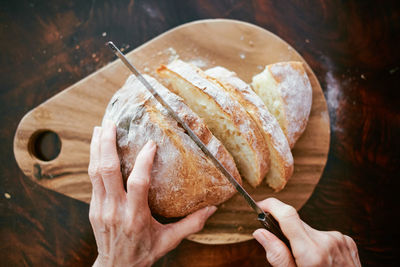 High angle view of person cutting bread on table