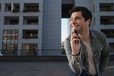 Young man using mobile phone while standing outdoors