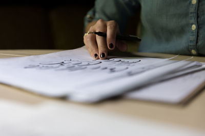 Cropped image of woman writing in book at table
