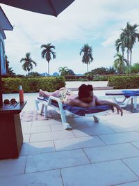 Woman relaxing on lounge chair against sky