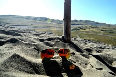 Low section of person on sand at beach against clear sky