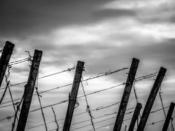 Low angle view of barbed wire fence against sky