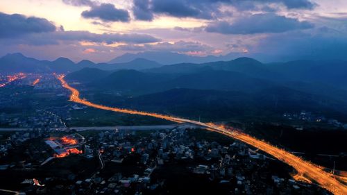 High angle view of illuminated city against sky at dusk