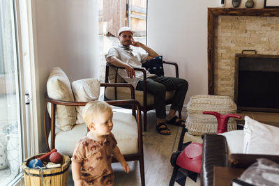 Rear view of woman using digital tablet while sitting at home