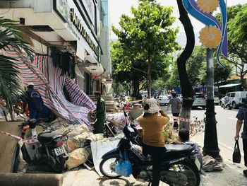 Rear view of people riding motorcycle on street in city