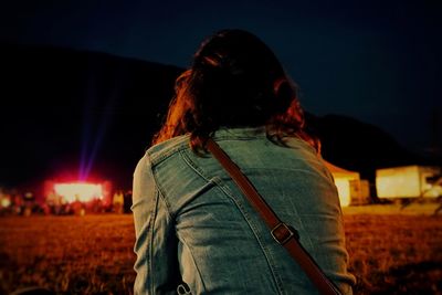 Rear view of woman sitting on field at night