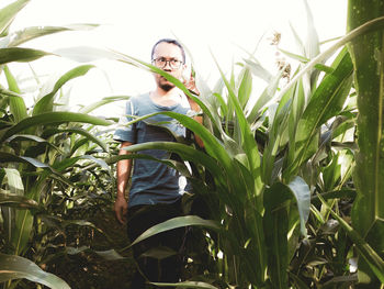 Young woman standing amidst plants on field