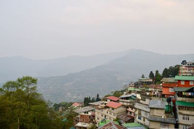 High angle view of town on hill against mountain during foggy weather
