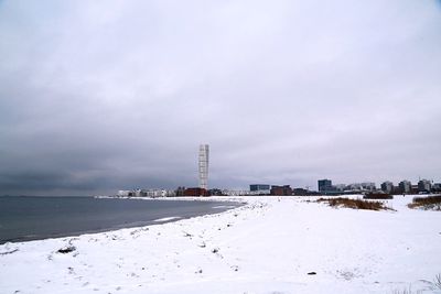 Beach in city against sky during winter