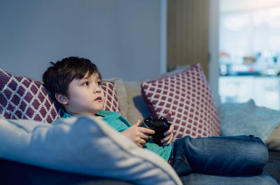 Rear view of boy using mobile phone at home