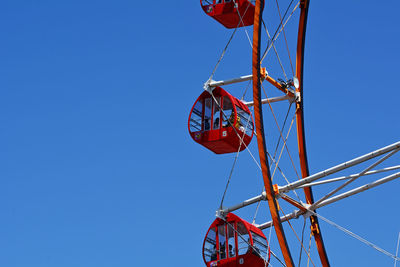 Low angle view of ferris wheel against clear blue sky