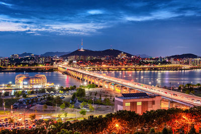 Illuminated bridge over river in city at night