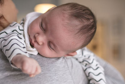 Close-up of mother carrying sleeping baby boy at home