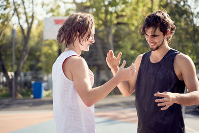 Cheerful friends shaking hands at basketball court