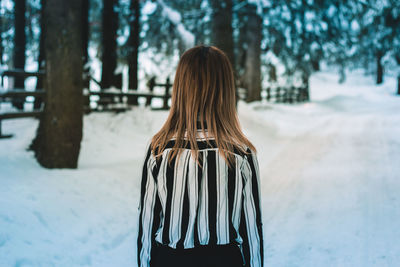 Rear view of woman standing on snow covered land