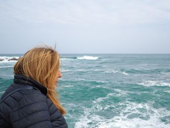 Side view of woman looking at sea against sky