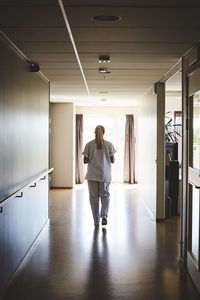 Full length rear view of female nurse walking in hospital corridor
