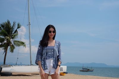 Young woman standing by beach against sky