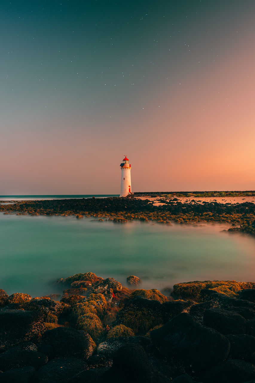 lighthouse, guidance, sky, water, tower, scenics - nature, building exterior, safety, architecture, sea, protection, security, built structure, building, nature, direction, night, sunset, beauty in nature, no people, horizon over water, outdoors