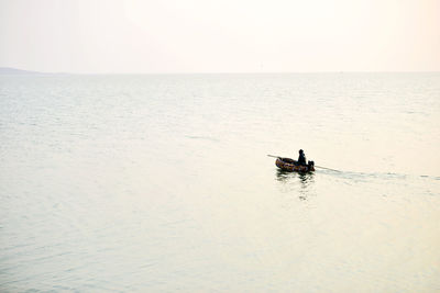 Silhouette man in boat on sea against sky