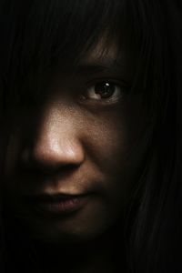 Close-up portrait of young woman in dark